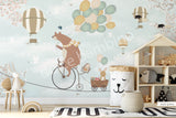 A wall mural featuring a cartoon bear riding a bicycle with a hot air balloon and various other playful animals, on a mint green background.