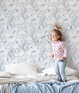 Child standing on a bed with floral wallpaper in the background