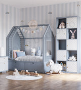 A children's bedroom featuring a gray house-shaped bed. The room has light gray and white striped wallpaper and a wooden floor