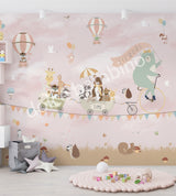 A whimsical wall mural featuring a bear on a bicycle with a wagon full of various cartoon animals, set against a pink background with hot air balloons and a cloudy sky.