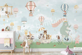 Large nursery wall mural in mint green and green tones featuring hot air balloons floating among birds and cherry blossom branches. A mint-green bear rides a vintage bicycle while woodland animals travel in a wagon below, creating a whimsical storybook scene for a baby's room