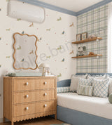 A styled children's bedroom featuring a wall with whimsical dog and cat illustrations, a plaid wallpaper border, a light wood bed, and a wooden cabinet with toys.
