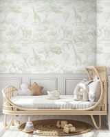 Children's room with a white wall with green animal prints,wicker crib,and toys.