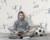 Child sitting against a soccer themed wallpaper