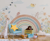 Children's room with a rainbow mural, toys, and a giraffe plush toy.