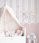 Children's bedroom with striped pattern with scallop wallpaper, a canopy bed, stuffed animals, and decorative wall art.