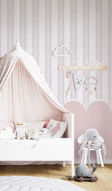 Children's bedroom with striped wallpaper with scallop,a pink tent, white crib, and toys on a wooden floor.