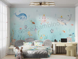 A room with 'Under the Sea' themed wallpaper featuring illustrations of sea creatures such as an octopus, whale, sea horses, and starfish in pastel colors. The room is styled with sea-themed bedding, a sofa, and decorative items.