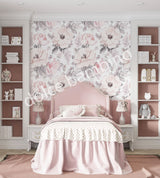 A section of pink wallpaper with a floral pattern, showcasing magnolia flowers, applied on a wall in a room with furniture.
