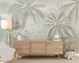 A section of wallpaper with a design of coconut trees and palm leaves in various shades of green, displayed in a room setting.