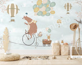 A wall mural featuring a cartoon bear riding a bicycle with a hot air balloon and various other playful animals, on a mint green background.