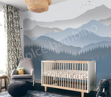 Nursery room with a crib, armchair, and mountain mural on the wall.