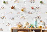 A room with walls covered in a wallpaper featuring Nordic pastel rainbows, fluffy clouds, and heart-shaped confetti.