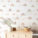 A room with walls covered in a wallpaper featuring Nordic pastel rainbows, fluffy clouds, and heart-shaped confetti.