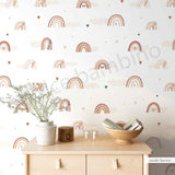 A room with walls covered in a wallpaper featuring Nordic pastel rainbows, fluffy clouds, and heart-shaped confetti.