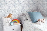 Children's bedroom with a floral-patterned wallpaper,teddy bear, rainbow toy.
