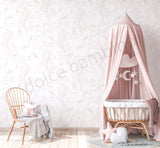 Children's room with a floral patterned wallpaper,crib under a pink canopy, and chair with a patterned cushion