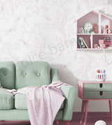 Green sofa with a floral print wallpaper, pink blanket in a room with a decorative wall and shelves.