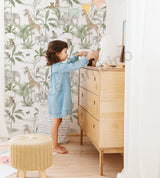 Kids room featuring safari wallpaper with elephants, giraffes, and tropical leaves, paired with natural wood furniture.