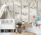 A wall mural featuring cartoon pandas in a forest setting, with trees and a blue sky, applied in a room with a crib and wooden furniture.