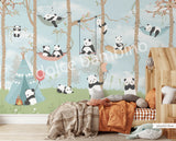 A wall mural featuring cartoon pandas in a forest setting, with trees and a blue sky, applied in a room with a bed and wooden furniture.