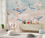 A Whale of a Time themed wall mural featuring a humpback whale, lighthouses, fish, seahorses, jellyfish, and starfish, with hot air balloons in the sky, installed on a wall in a room with children's furniture.