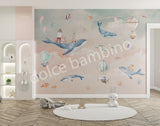 A Whale of a Time themed wall mural featuring a humpback whale, lighthouses, fish, seahorses, jellyfish, and starfish, with hot air balloons in the sky, installed on a wall in a room with children's furniture.
