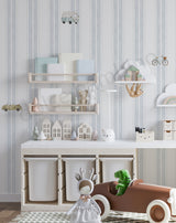 A styled children's room corner featuring light blue and white vertically striped wallpaper, a white storage cabinet,floating shelves, wall-mounted cloud shelves, and a brown wooden toy car with a green dinosaur inside.