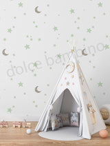White teepee tent with decorative elements in a child's room with star and moon wallpaper.