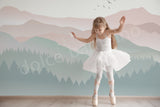 Young girl in a ballet outfit standing in a dance pose against a wall with mountain mural.