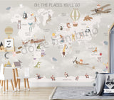 Children's room featuring a colorful world map wallpaper with illustrations of animals and vehicles. A wooden dresser and a canvas storage basket are visible in the room.