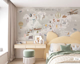 Children's room featuring a colorful world map wallpaper with illustrations of animals and vehicles. A wooden dresser and a canvas storage basket are visible in the room.