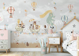 A whimsical wall mural featuring a bear on a bicycle with a wagon full of various cartoon animals, set against a grey background with hot air balloons and a cloudy sky.