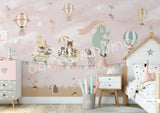 A wall mural featuring a cartoon bear riding a bicycle with a hot air balloon and various other playful animals, on a dusty rose background.