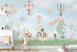 Large nursery wall mural in baby blue and dark green tones featuring hot air balloons floating among birds and cherry blossom branches. A mint-green bear rides a vintage bicycle while woodland animals travel in a wagon below, creating a whimsical storybook scene for a baby's room
