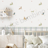 A styled children's bedroom featuring a wall with whimsical dog and cat illustrations, a plaid wallpaper border, a light wood bed, and a wooden cabinet with toys.