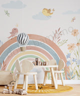 Children's play area with a rainbow mural, table, chairs, and toys on a light wooden floor.