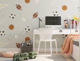 A room with walls covered in 'Spry Sports' wallpaper featuring a pattern of soccer balls, basketballs, footballs, tennis rackets, and cricket bats.