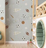 A room with walls covered in 'Spry Sports' wallpaper featuring a pattern of soccer balls, basketballs, footballs, tennis rackets, and cricket bats.