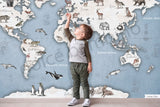 A wall mural featuring a watercolor animal world map with various continents, oceans, and wildlife illustrations, displayed in a room setting with furniture.