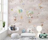 A wall mural featuring whimsical animal characters in a sky with hot air balloons, presented in a room setting with a toys and chair